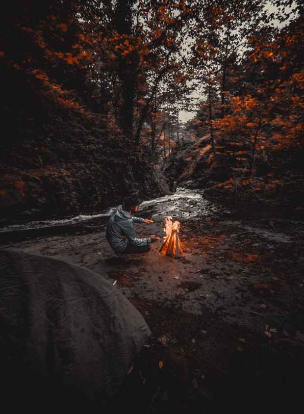 man wearing grey hoded jacket beside bonfire
