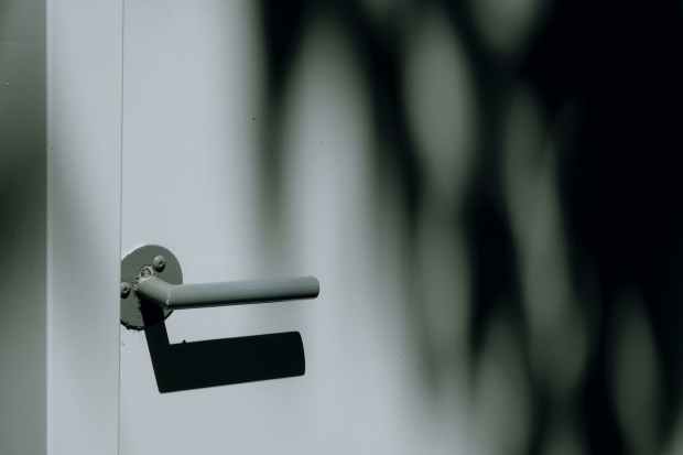 grayscale photo of gray door lever and white door panel